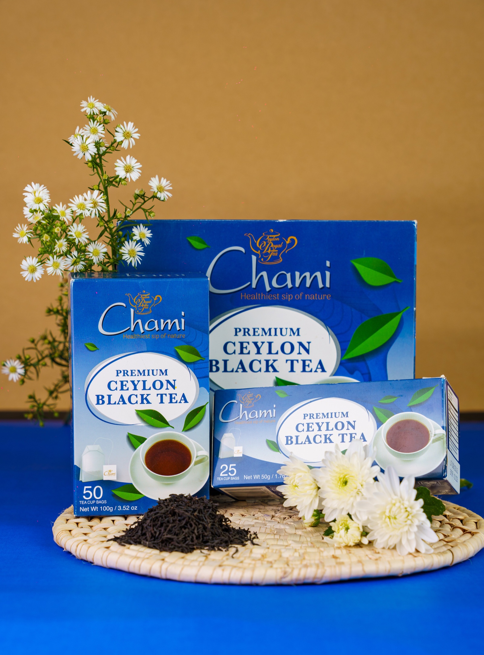 Chami Premium Ceylon Black Tea boxes and tea cup on a wooden table with chamomile flowers